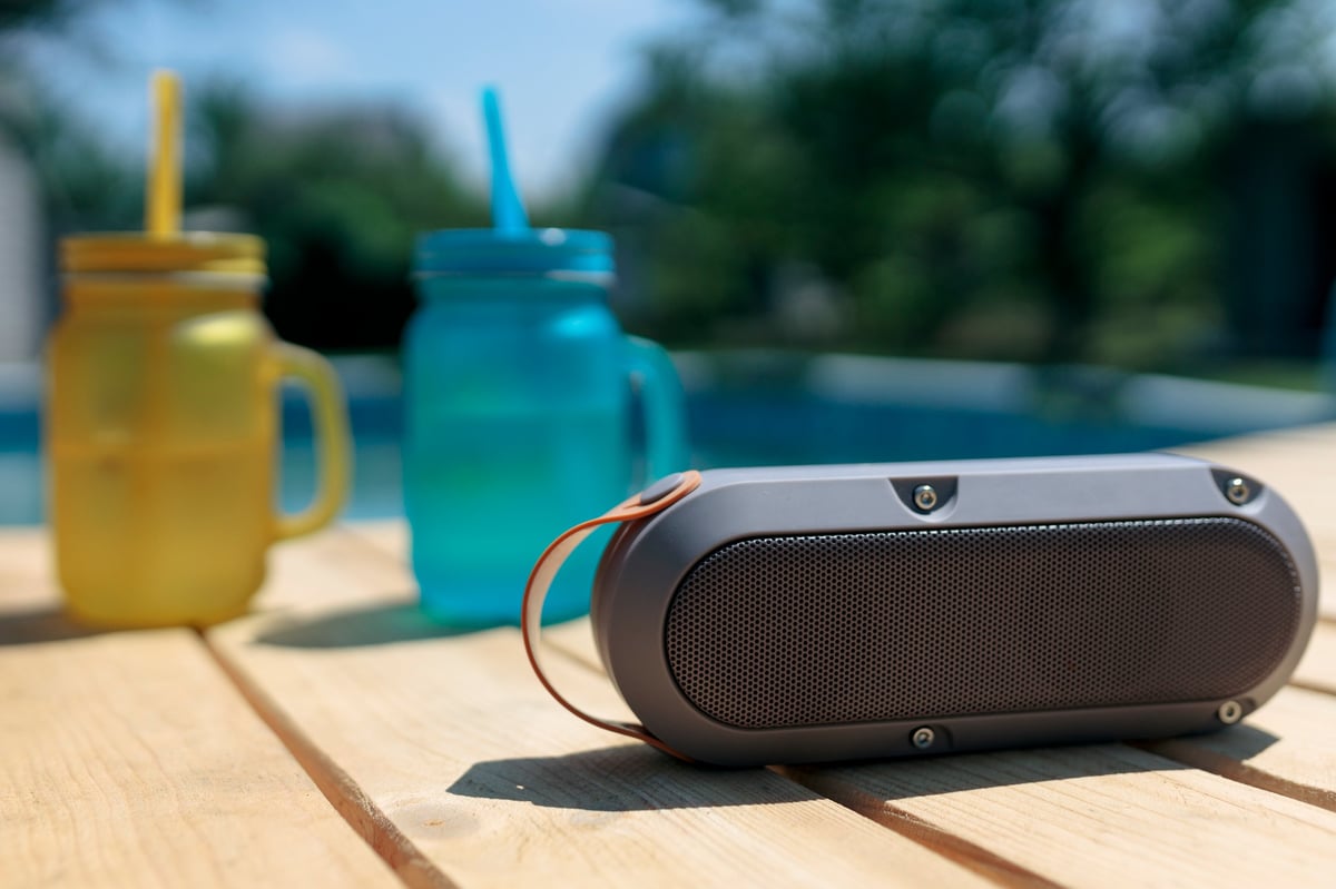 Portable speaker and cocktails by a pool at a summer party
