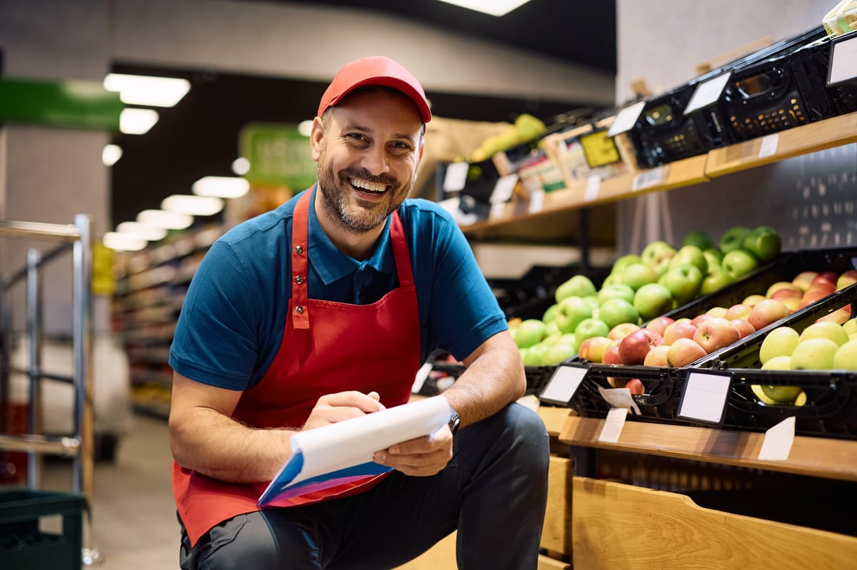 Happy man working at fresh fruit section in supermarket